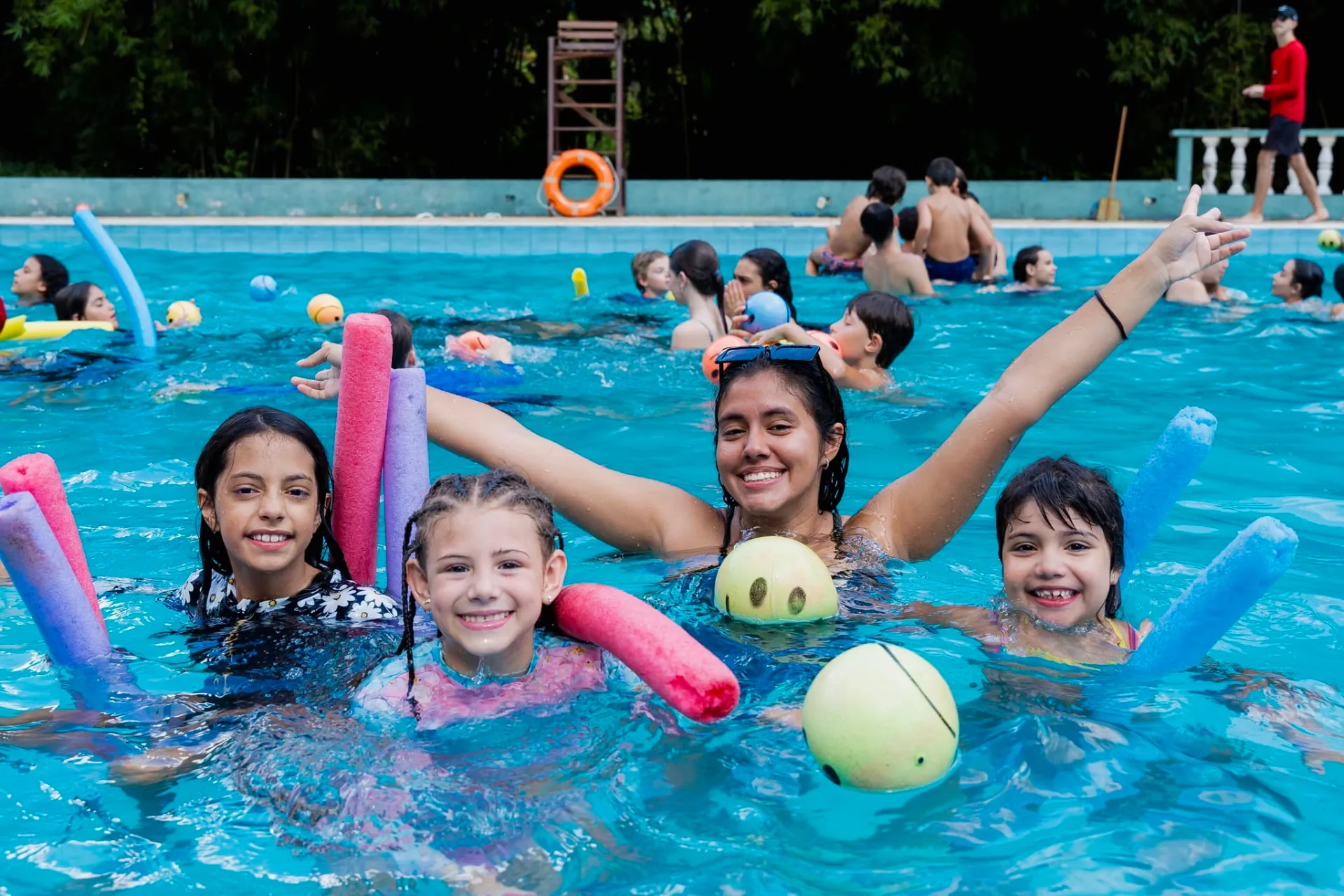 Crianças brincando na piscina acompanhadas por uma equipante da Temporada Kids