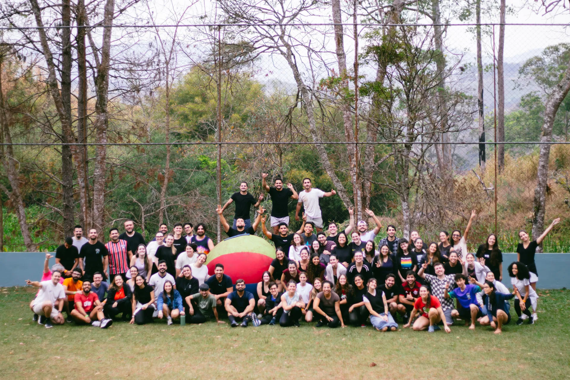 Grande grupo de jovens adultos reunido no campo durante o Acampa 25+