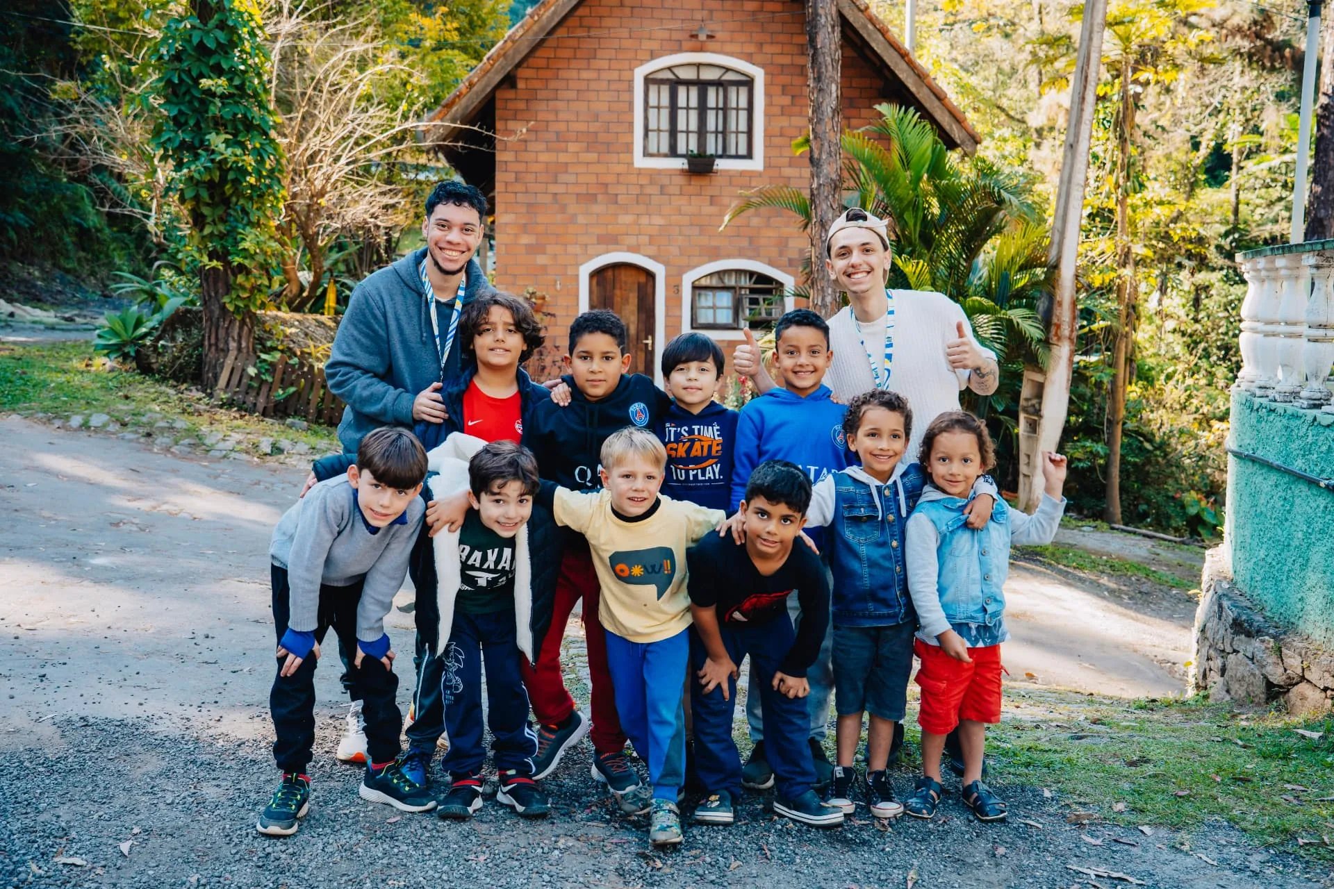 Crianças da Temporada Kids acompanhadas por dois equipantes em frente ao alojamento