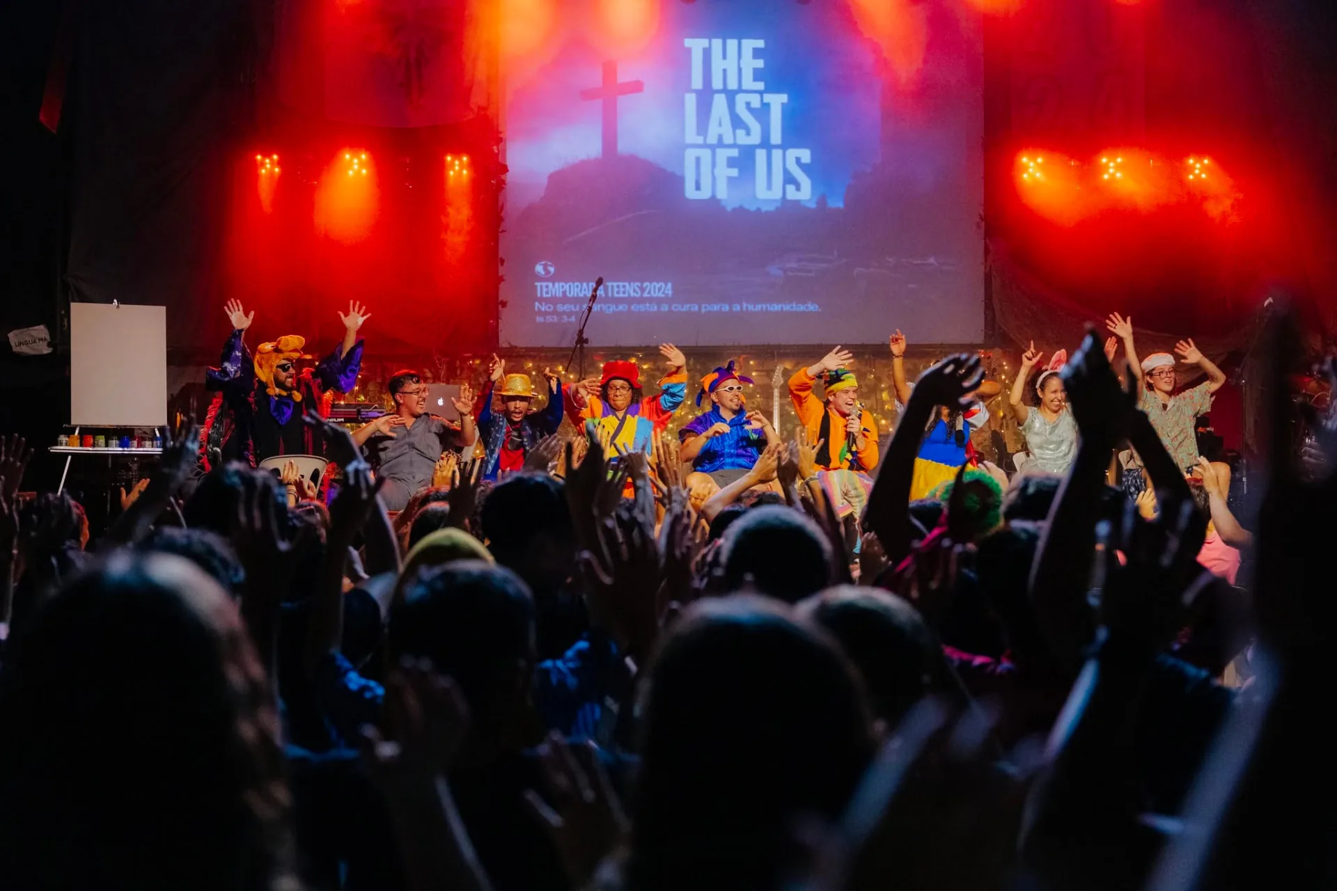 Adolescentes participando de uma programação coletiva com música e apresentação no palco
