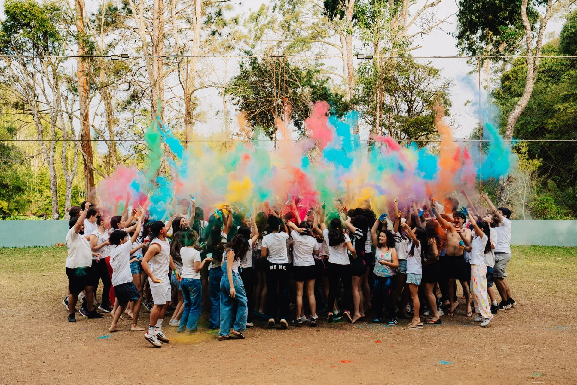 Adolescentes celebrando juntos em meio a uma explosão de pós coloridos na Temporada Teens