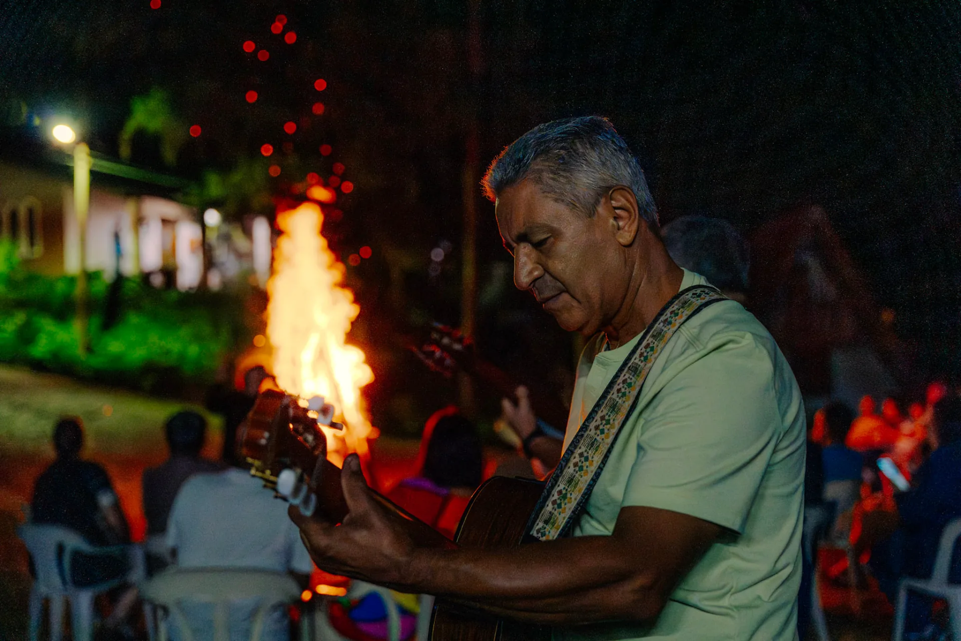 Músico tocando violão diante da fogueira no Acampa 50+